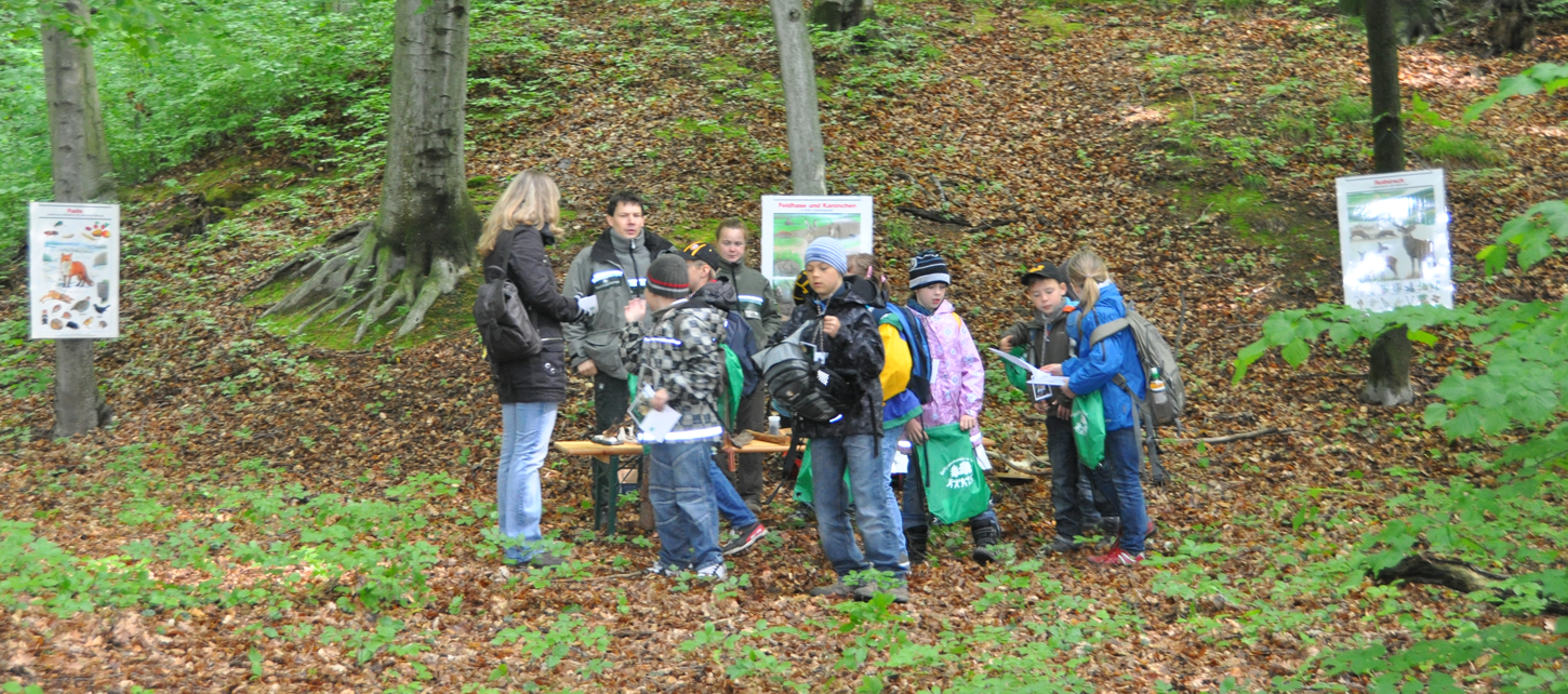 Kindergruppe mit Lehrerin und Förster im Wald