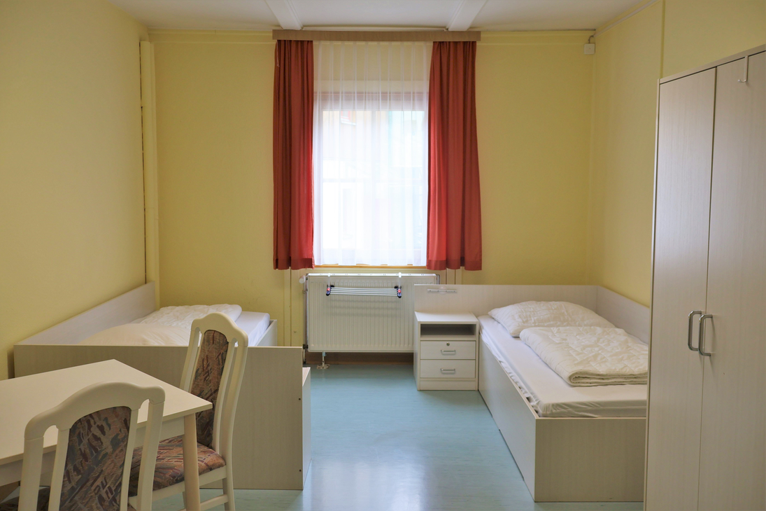 Das Betreuerzimmer mit zwei Betten, einem Schrank und einem Tisch.